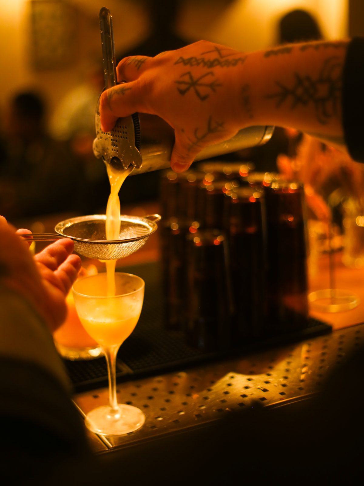 Bartender coando drink autoral em coqueteleira